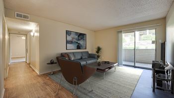 A living room with a chair, a couch, and a painting on the wall.